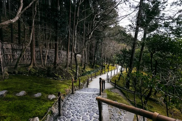 A stone-paved garden path with a wooden handrail winding down through moss and tall trees